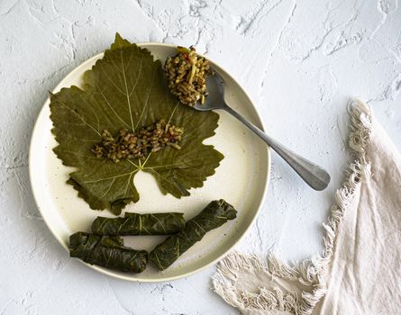 Dolma yalanji served on a decorative white plate with a textured background.