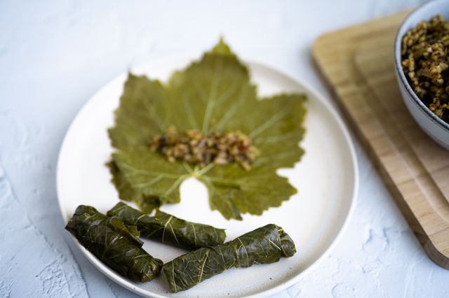 Close-up of dolma yalanji with grape leaves on a white plate, top view.