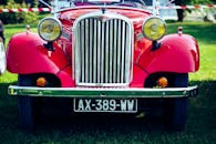 一辆经典的红色老式汽车在户外草地上公开展览