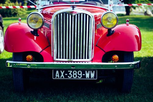 Free Front view of a classic red vintage car at an outdoor public exhibition on grass. Stock Photo