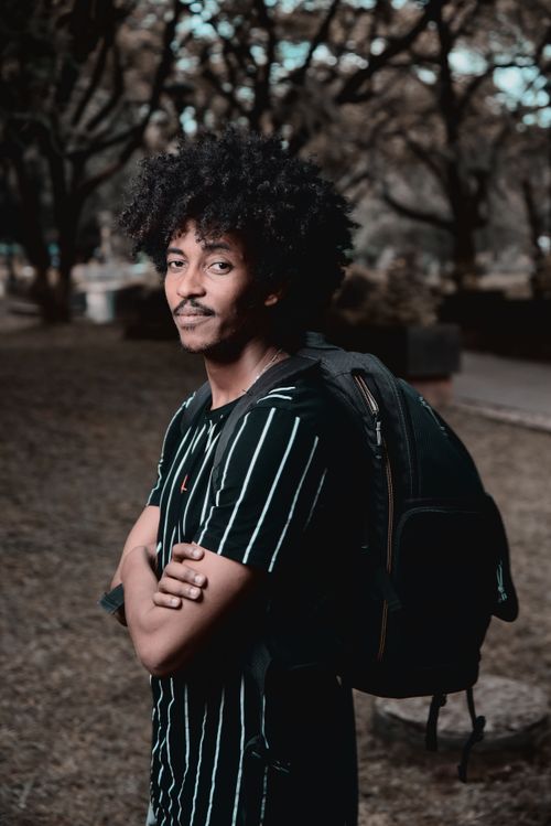 Free Young man with afro hair poses confidently outdoors, showcasing casual fashion in an Ethiopian park. Stock Photo