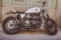 一辆经典摩托车停在垃圾墙前，展示出其时尚的复古设计