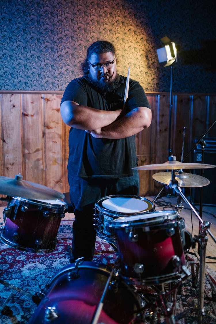 Man Standing In Front Of A Drum Set In Black Shirt Holding Drumsticks