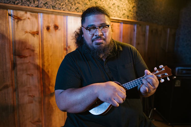 Man In Black Polo Shirt Playing A Ukelele