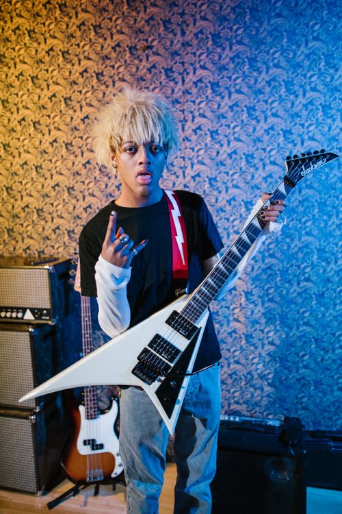 Free Energetic young musician posing with electric guitar in a stylish indoor music studio. Stock Photo
