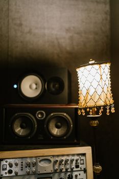 A cozy music studio featuring speakers and a vintage lamp adding warmth to the atmosphere.