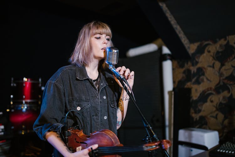 A Woman Singing While Holding A Violin