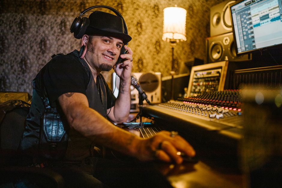 Smiling music producer using audio equipment in a recording studio.