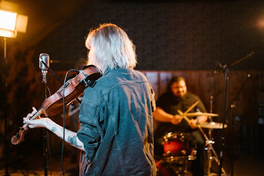 Musicians playing violin and drums in a well-lit studio setting, creating a lively musical atmosphere.