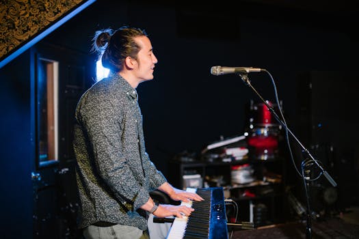 A musician playing an electronic keyboard in a studio with a microphone stand nearby.