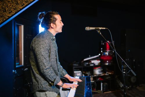 Free A musician playing an electronic keyboard in a studio with a microphone stand nearby. Stock Photo
