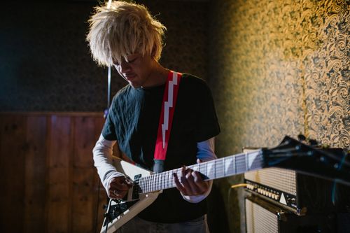 Free A young musician plays an electric guitar passionately in a cozy indoor music studio setting. Stock Photo