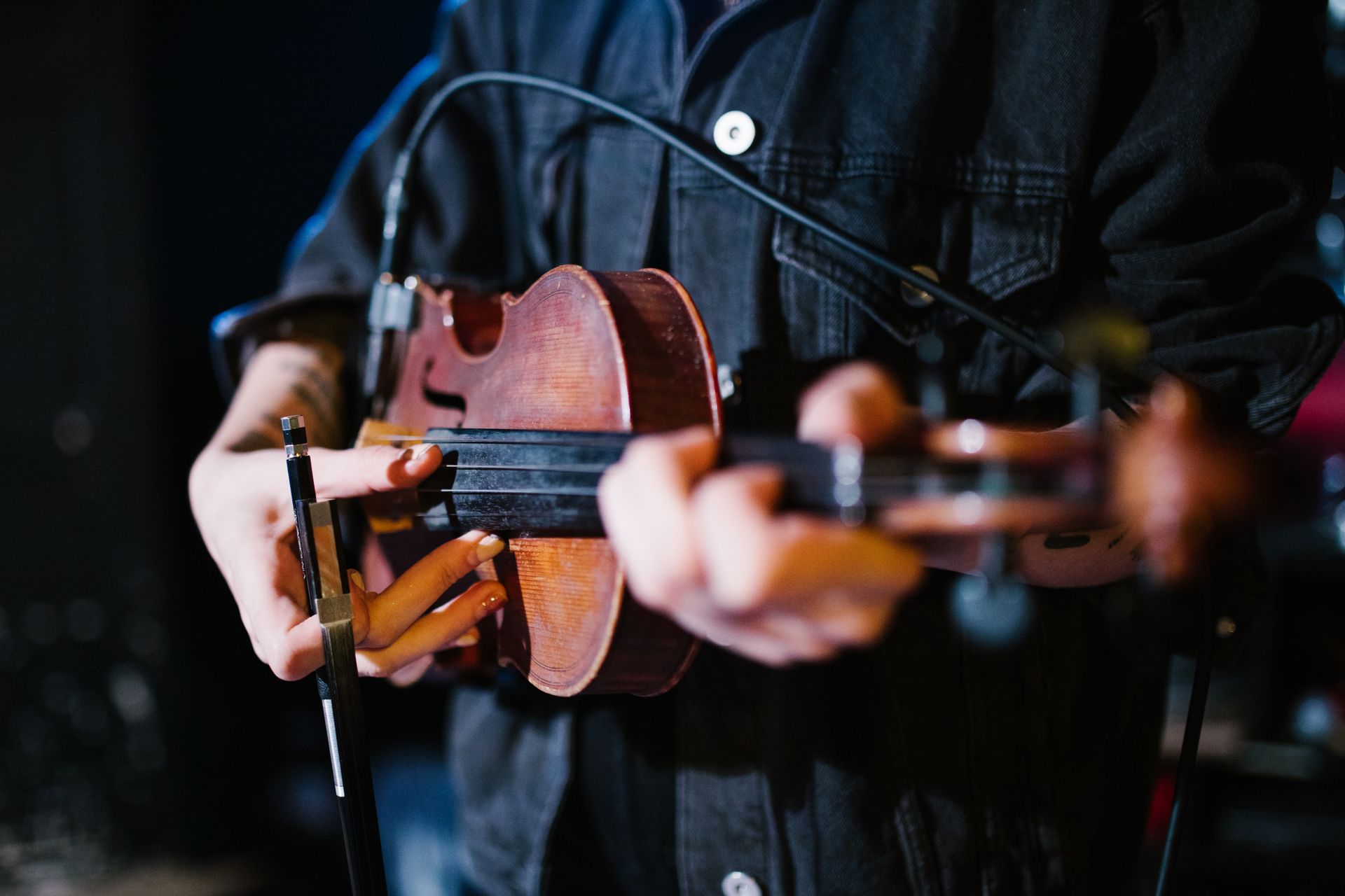A musician passionately plays the viola on stage, capturing the essence of live performance.
