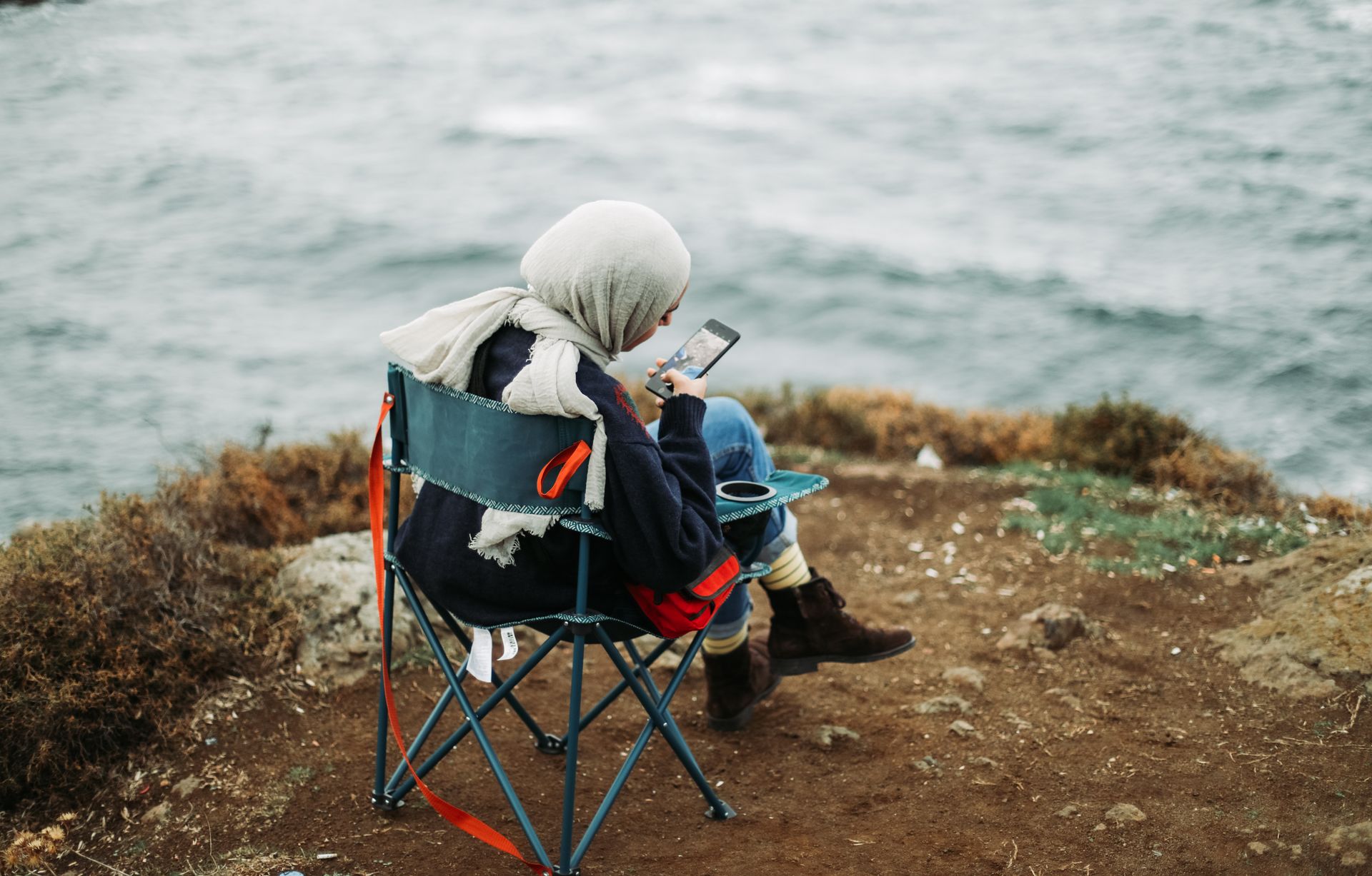 Woman Sitting on a Folding Chair on a Cliff