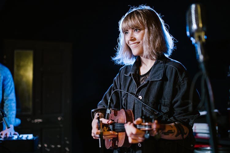 A Woman In Black Jacket Playing Violin