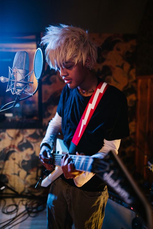 Free Portrait of a young musician playing electric guitar in a studio setting. Stock Photo