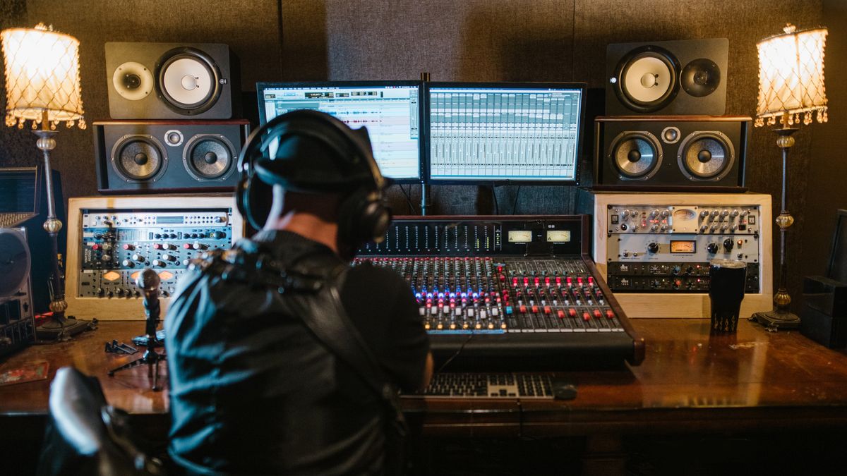 Music producer working with computer and mixing console in recording studio