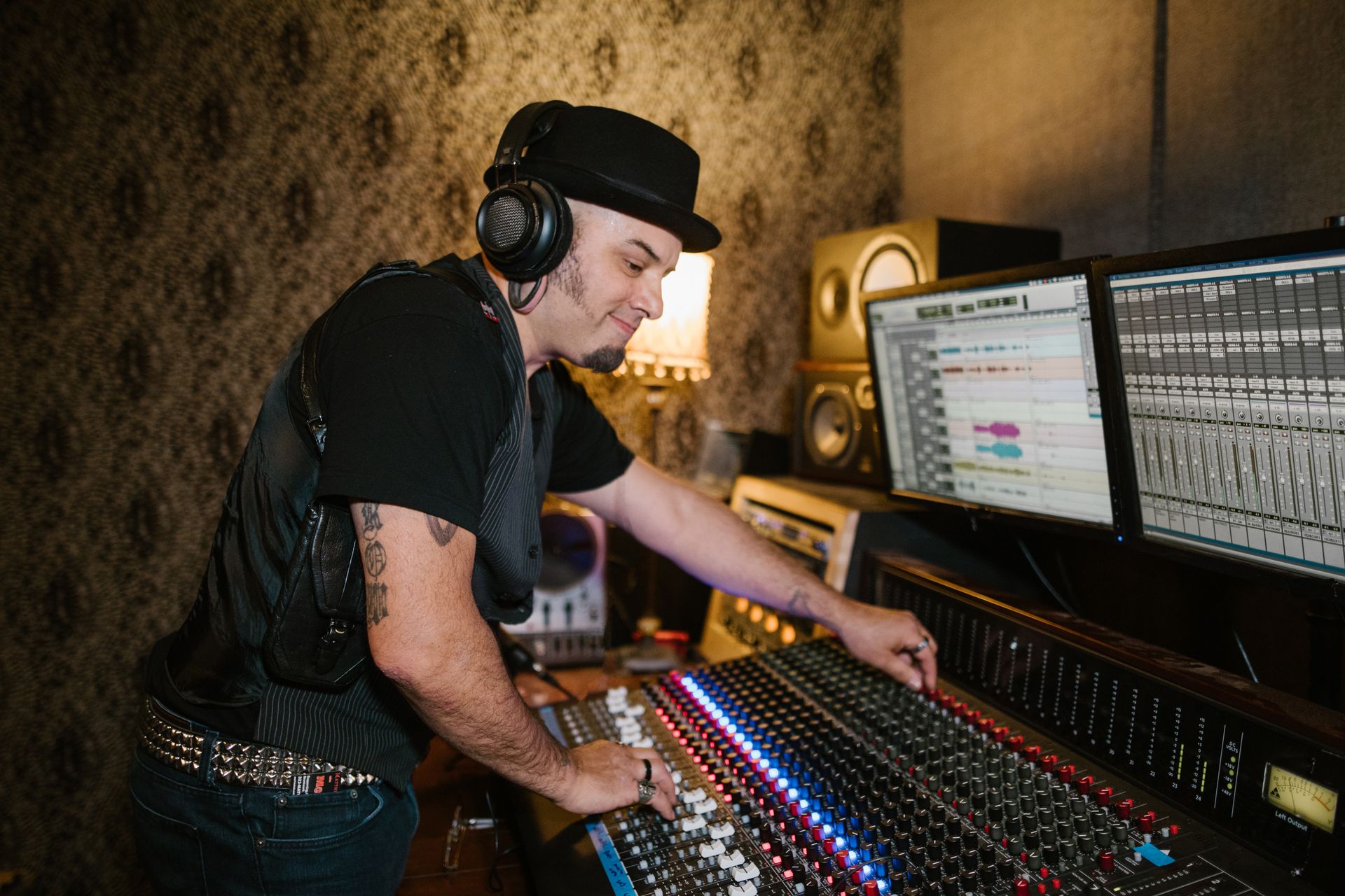 A focused audio engineer adjusts sound levels on a control panel in a modern recording studio.
