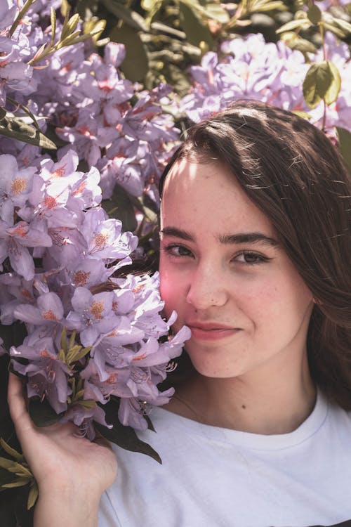 Smiling Girl Against a Blooming Flower Bush