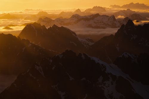 Free A breathtaking aerial view of snow-capped mountains at sunrise in British Columbia, Canada, enveloped in golden light. Stock Photo