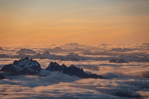 Free A breathtaking view of snow-capped peaks emerging from clouds during sunrise in British Columbia, Canada. Stock Photo
