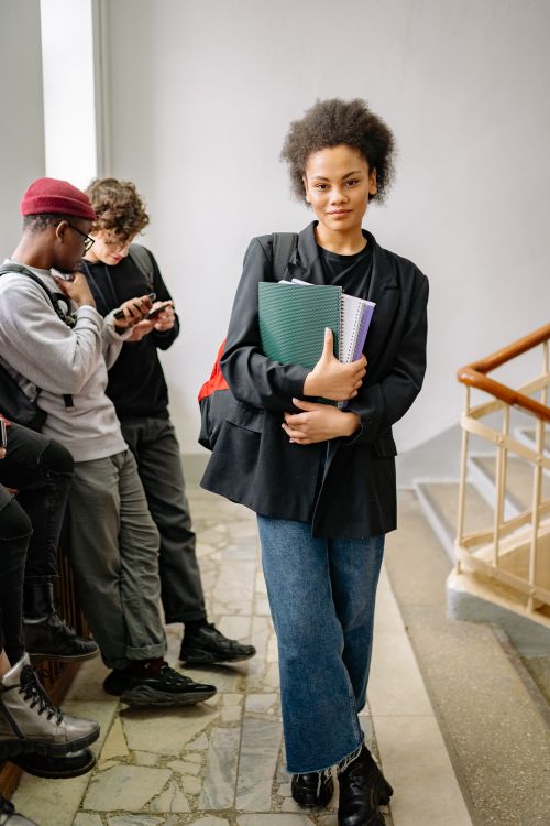 Free A stylish student confidently carrying books, showcasing college life in an educational setting. Stock Photo
