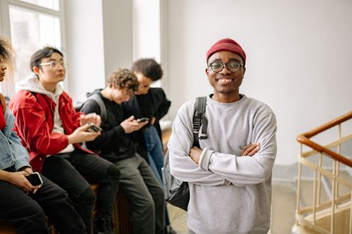 Free A diverse group of university students indoors, featuring a smiling young man in the foreground. Stock Photo