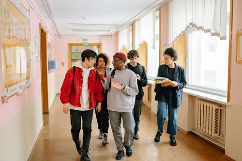 Free A diverse group of college students walking and conversing in a university hallway. Stock Photo