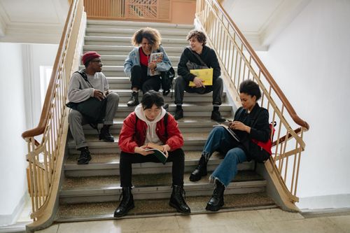 Free A diverse group of college students sitting on stairs, studying and socializing indoors. Stock Photo