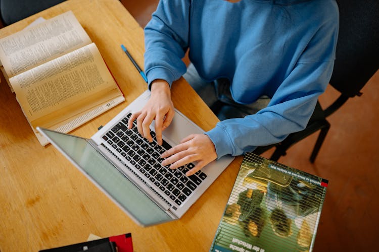 Person In Blue Sweater Using A Laptop