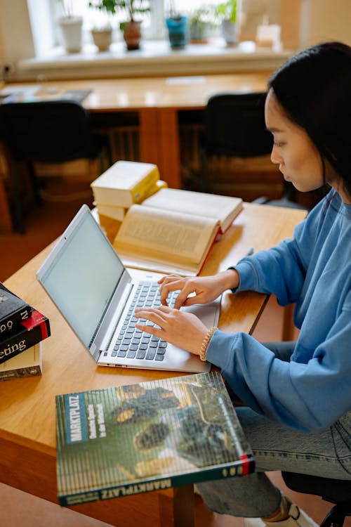 Woman in Blue Long Sleeve Shirt Using Silver Laptop