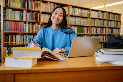 Free Woman in Blue Long Sleeve Shirt Sitting at the Table Smiling Stock Photo