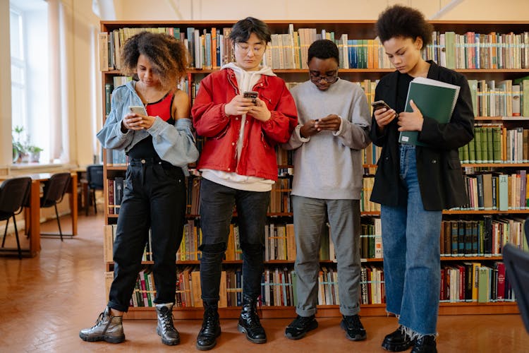 Group Of People Standing On Brown Wooden Floor Beside Brown Wooden Bookshelves