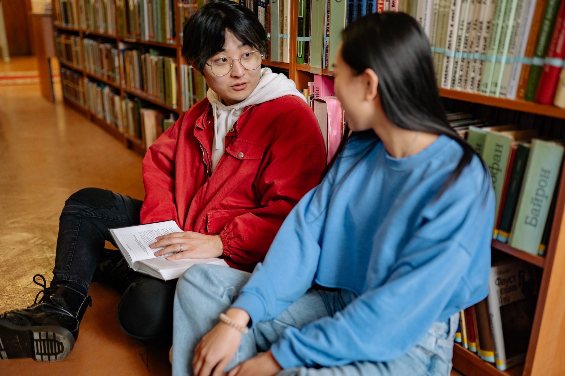 An international student diligently studying in a modern Korean university library, surrounded by books.
