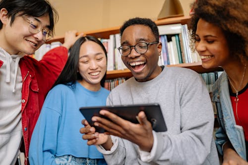 Free Man in Gray Sweater Holding Black Digital Table Smiling Stock Photo