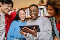 Man in Gray Sweater Holding Black Digital Table Smiling