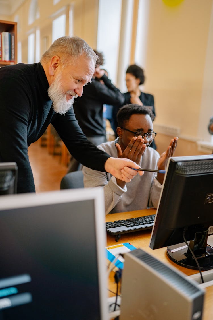 An Elderly Man Pointing Something On A Computer Screen