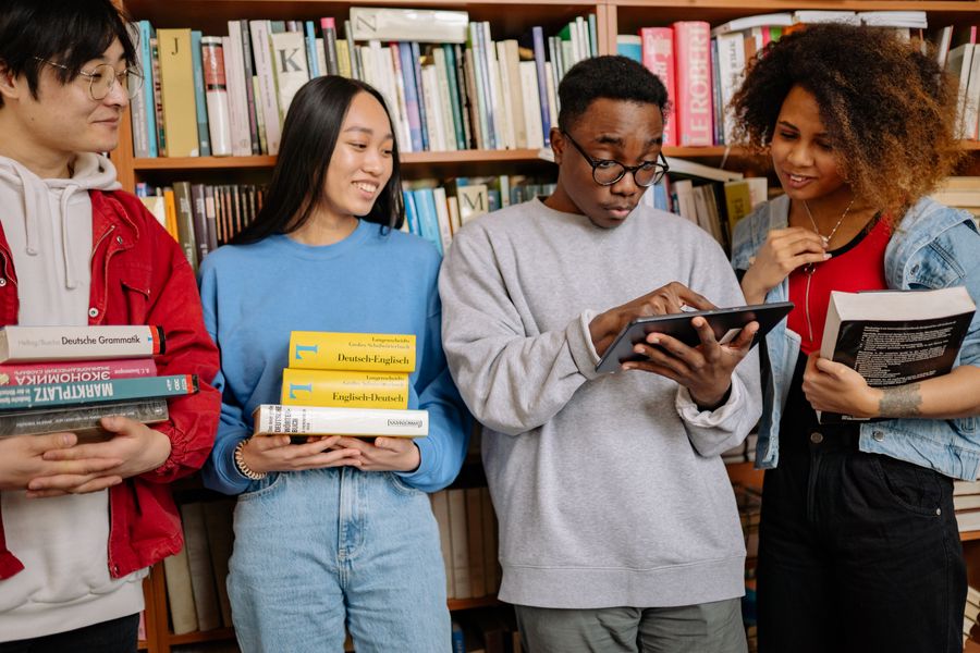 A group of diverse students studying together with books and a tablet