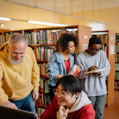 Diverse group of students and a teacher collaborating in a library
