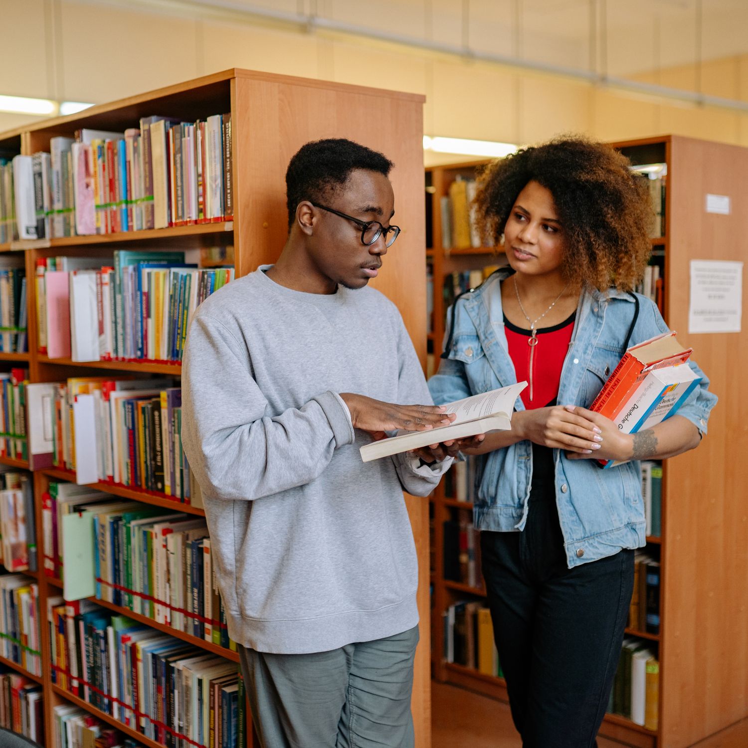 Man and Woman Standing Holding Books in a Library and Talking · Free ...