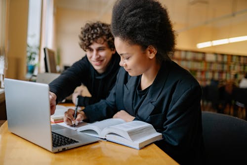 Free Man and Woman Studying while Writing on a Notebook Stock Photo