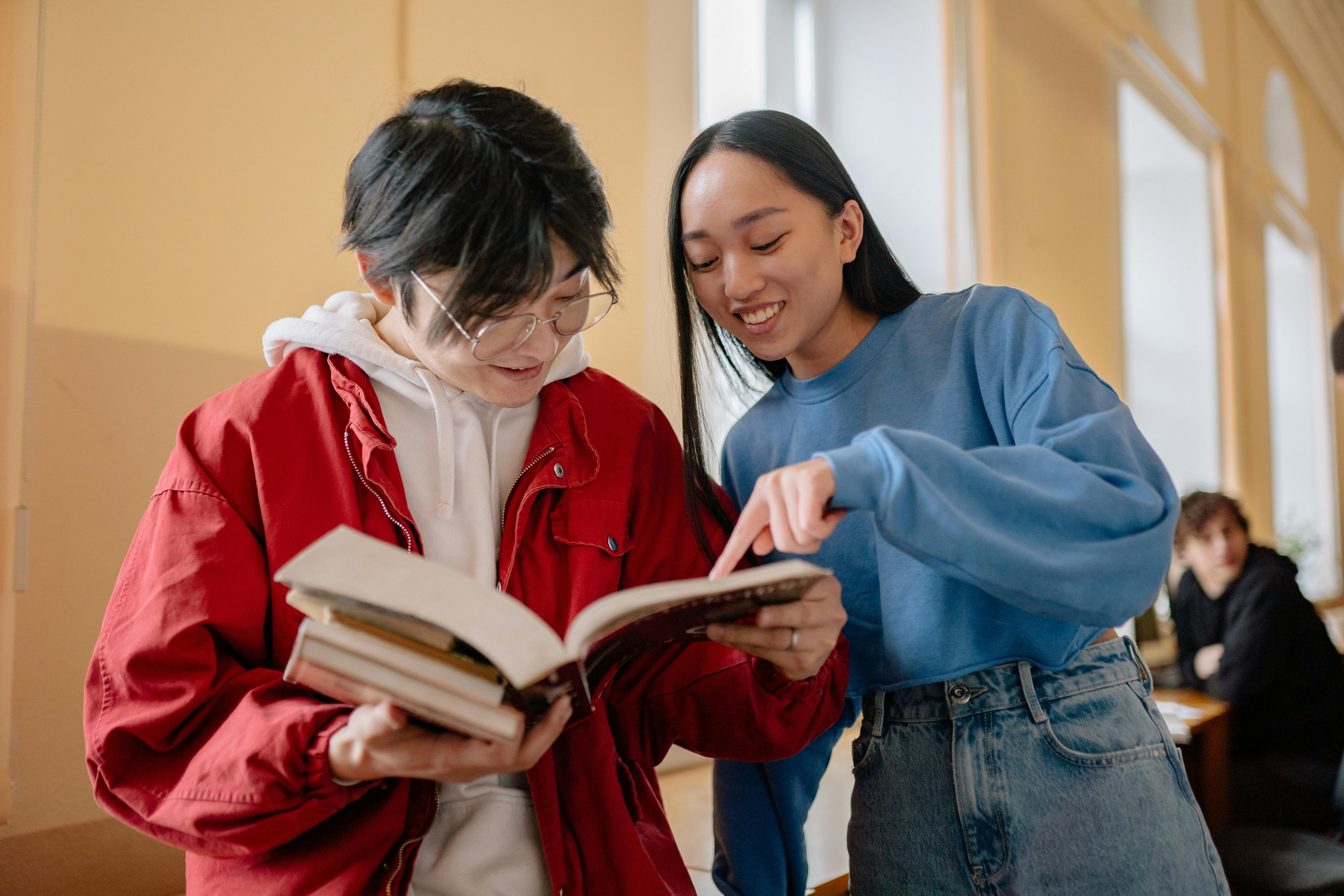 students standing in the hallway and looking at a textbook