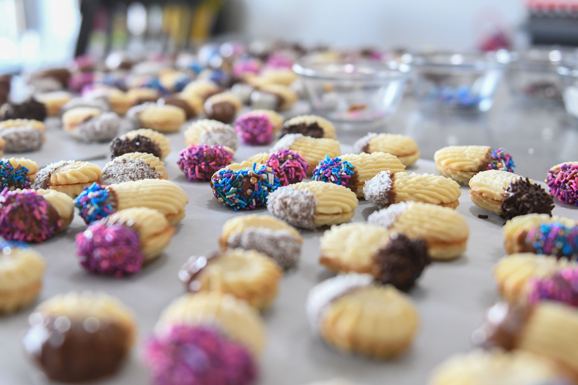 Close-up of colorful butter cookies with sprinkles on a baking surface.