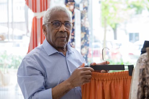 Free Senior man browsing clothing in a stylish boutique, holding pants. Stock Photo