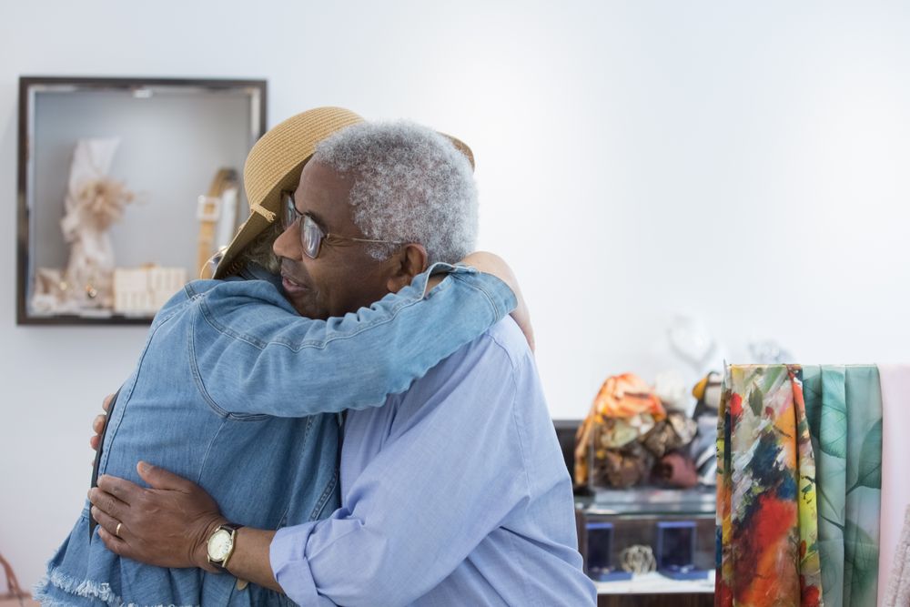 Two Black elders sharing a warm hug