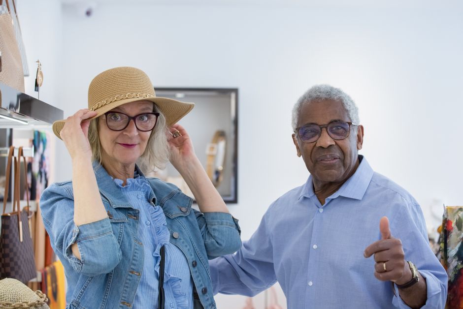 Elderly couple enjoying shopping for sun hats in a stylish store.
