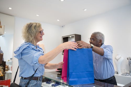 Clerk Passing Shopping Bags to Customer