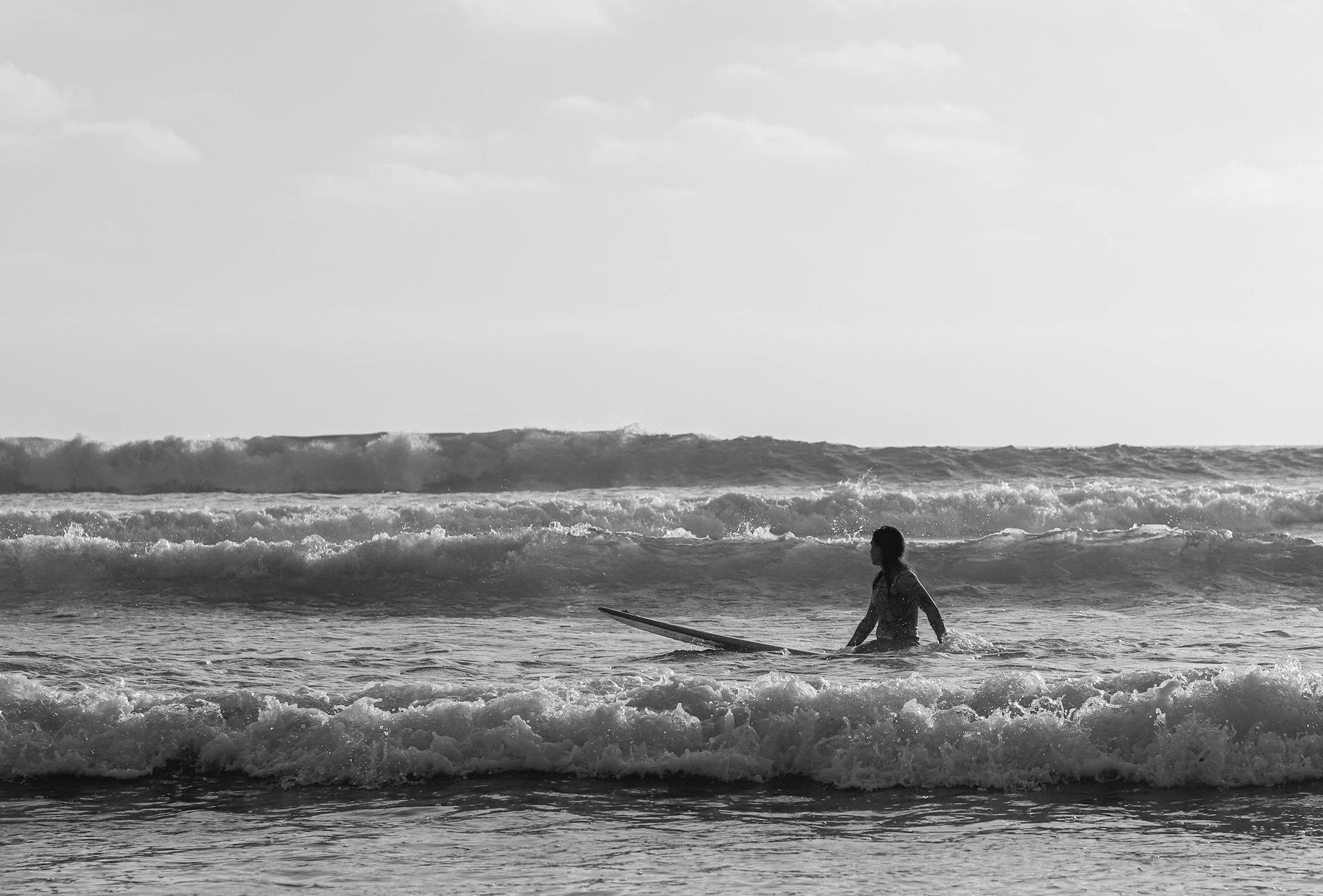 A woman with a surfboard in the waves at Huntington Beach, CA.