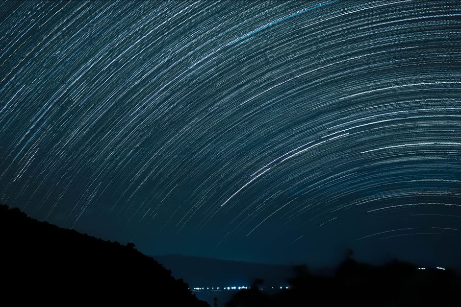 Fotógrafo em campo aberto fotografando a Via Láctea à noite com objetiva ultra-angular