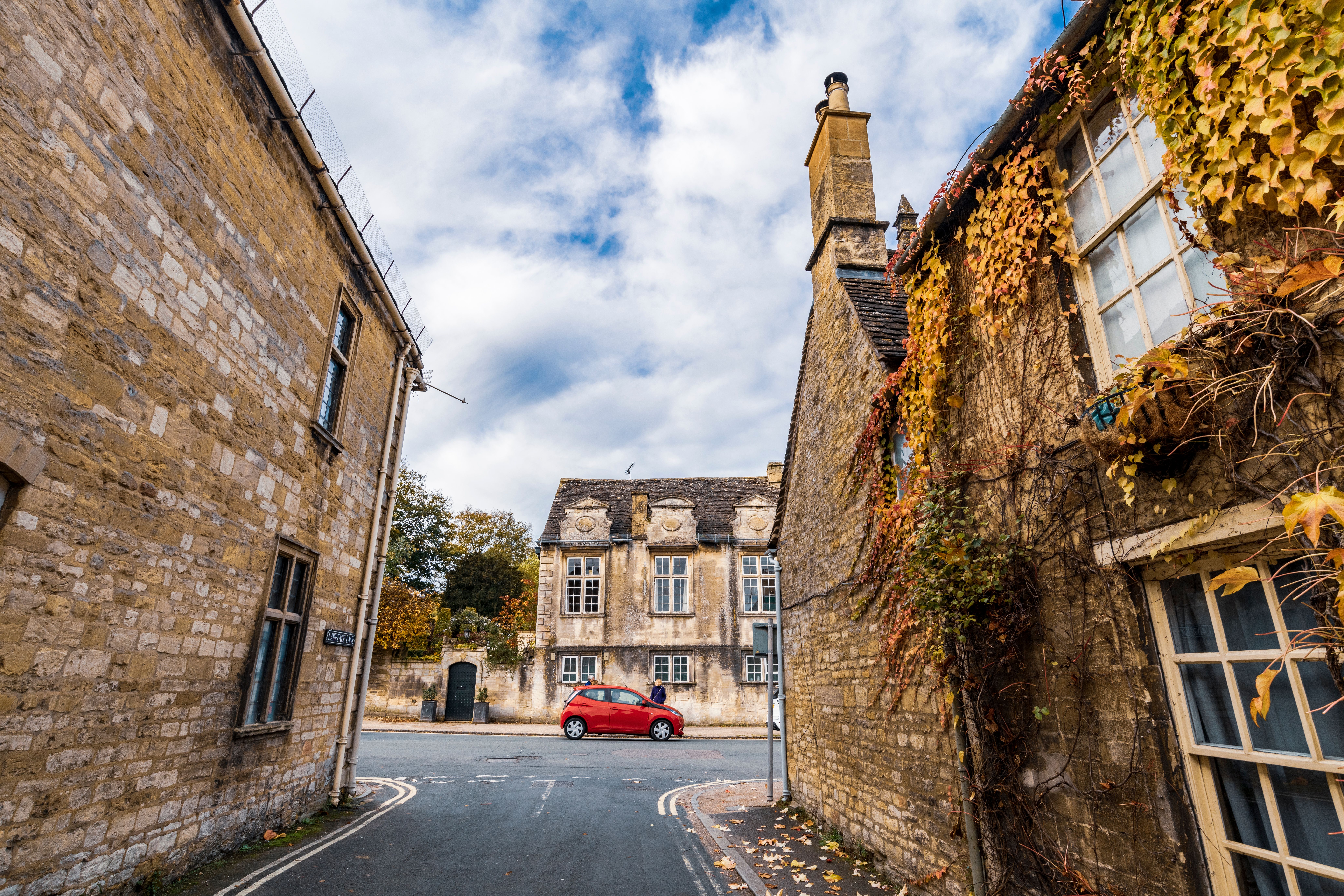 Explore the serene autumn charm of Burford's historic streets lined with ivy-covered stone houses.